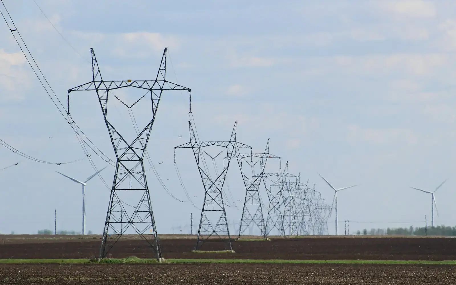 Transmission towers and wind turbines across open ground