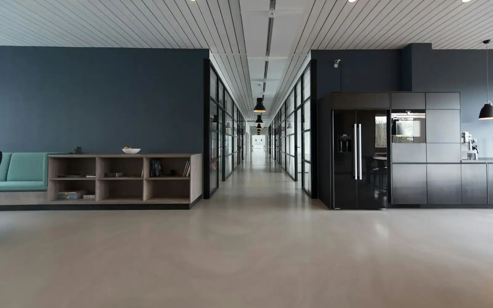 A long modern office corridor with dark walls and a glass ceiling
